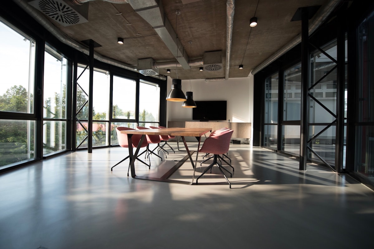 Long shared worktable running through a concrete and glass studio interior